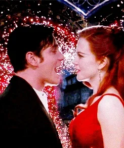 Nicole Kidman and Ewan McGregor in the vibrant red‑and‑gold theatrical poster for Moulin Rouge!, surrounded by ornate Parisian cabaret imagery.