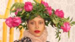 Erykah Badu on the red carpet at the 2019 BET Black Girls Rock! wearing an elaborate pink‑rose floral headpiece and bold beauty styling.