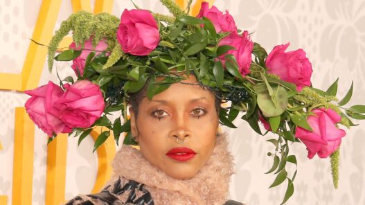Erykah Badu on the red carpet at the 2019 BET Black Girls Rock! wearing an elaborate pink‑rose floral headpiece and bold beauty styling.