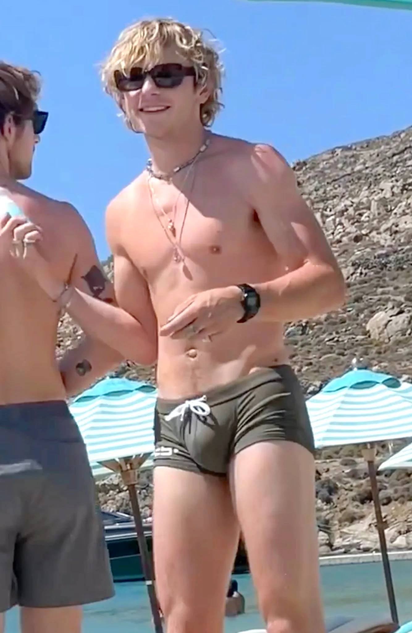 Ross and Rocky Lynch on the beach in Mykonos applying sunscreen during their 2023 vacation.