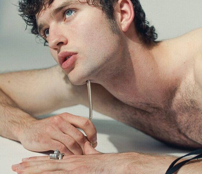 Model Leander Wilde posing with natural hair, rugged charm, and grey eyes.