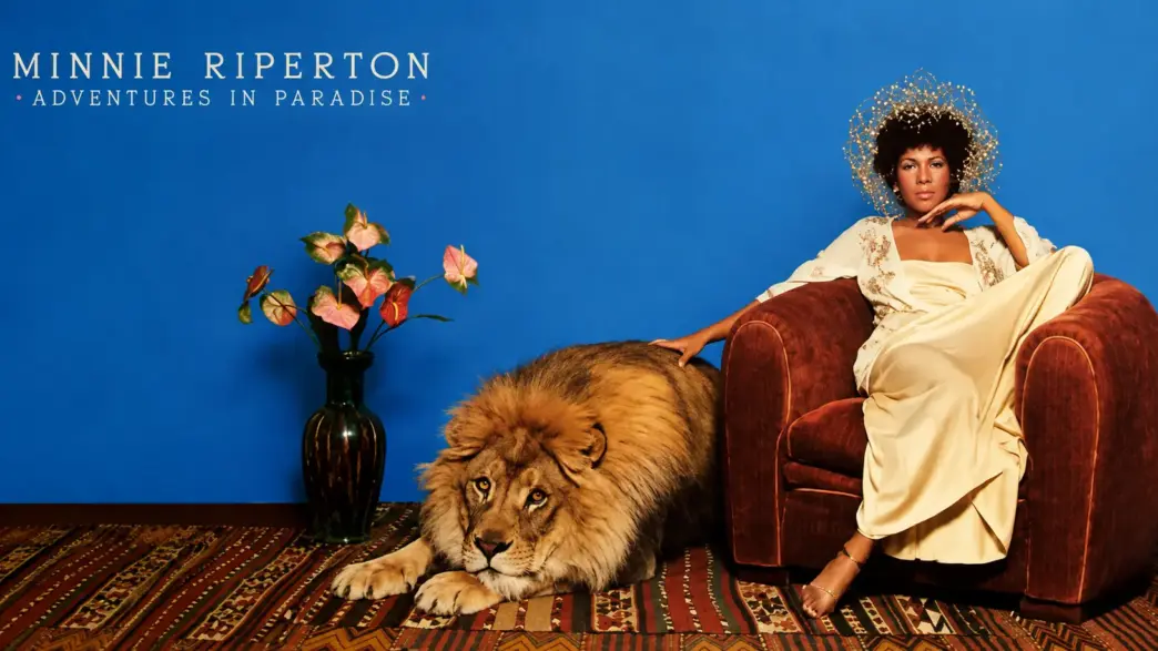 Minnie Riperton seated beside a lion in artwork inspired by her 1975 album Adventures in Paradise