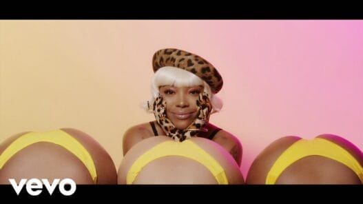 KaMillion posing in a fruit-filled scene from the I Heart Banana music video