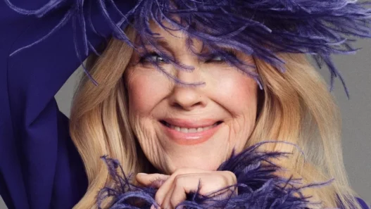 Catherine O’Hara by Jason Kim for Stylist in a lavender feathered outfit smiling.