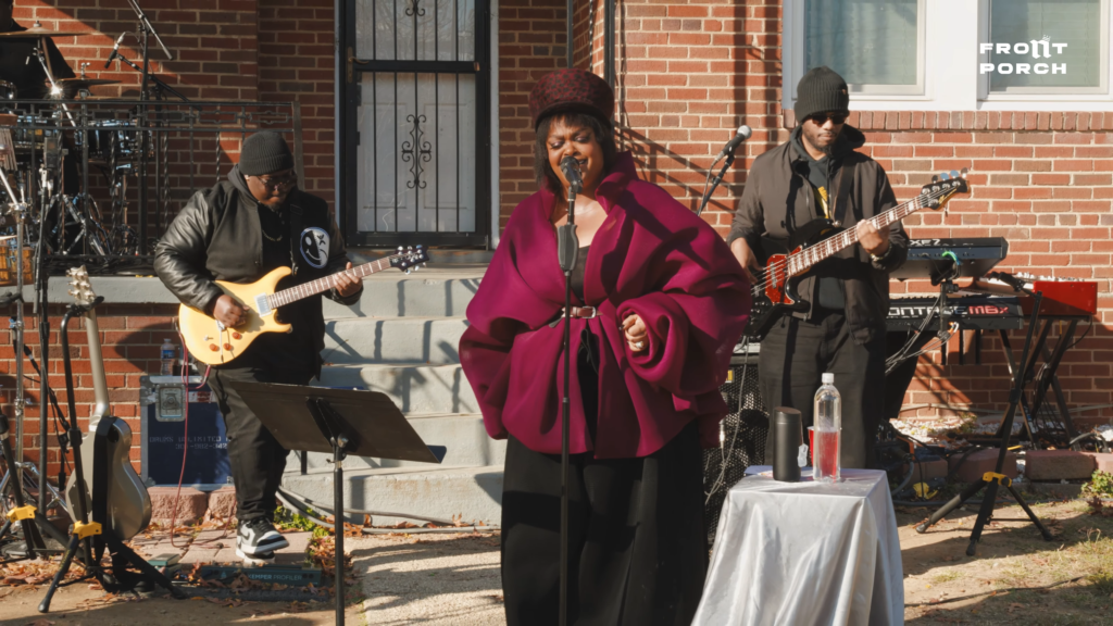 Jill Scott singing “Lifting Me Up” in outdoor setting