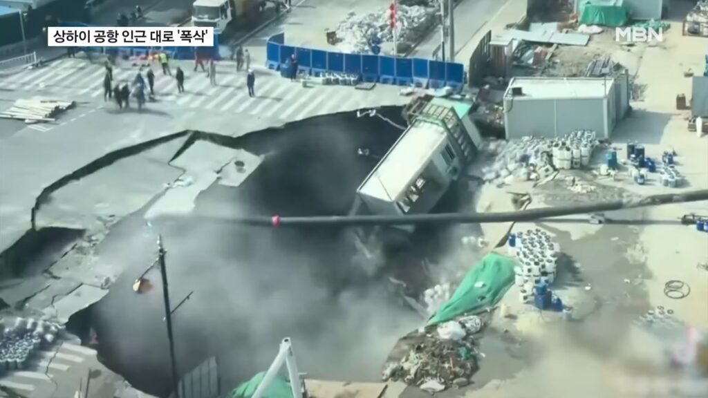 Road collapsing into a sinkhole in Shanghai as workers flee the scene.