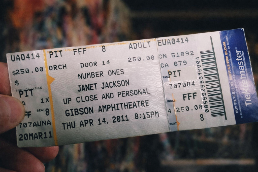 Close-up photo of a Janet Jackson “Up Close and Personal” concert ticket from April 14, 2011 at the Gibson Amphitheatre, showing the artist name, tour title, venue, date, and pit seating.

