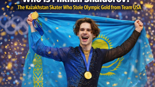 Mikhail Shaidorov of Kazakhstan celebrates after winning Olympic gold in men’s figure skating at the Milano Cortina Winter Games, holding his medal as confetti falls.