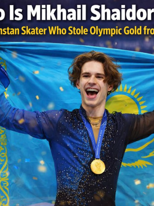 Mikhail Shaidorov of Kazakhstan celebrates after winning Olympic gold in men’s figure skating at the Milano Cortina Winter Games, holding his medal as confetti falls.