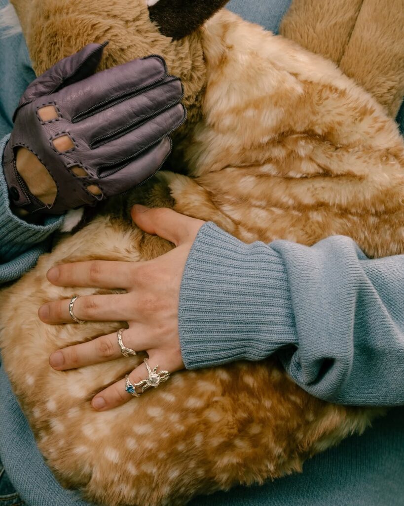 Close up of Mikhail Shaidorov jewelry adorned hands holding a plush animal