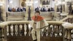 Young designer Max Alexander poses on a marble staircase at a historic Paris Fashion Week location.