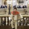 Young designer Max Alexander poses on a marble staircase at a historic Paris Fashion Week location.