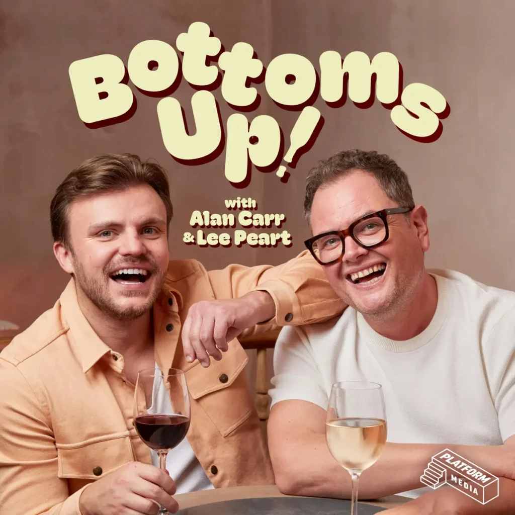 Two men smiling at a wine-filled table for a podcast promo, with 'Bottoms Up!' title above and hosts Alan Carr & Lee Pearce.