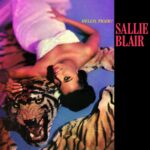 Poster for Salle Blair: a smiling woman in white atop a tiger rug with a tiger beside her, bold pink title on a black panel