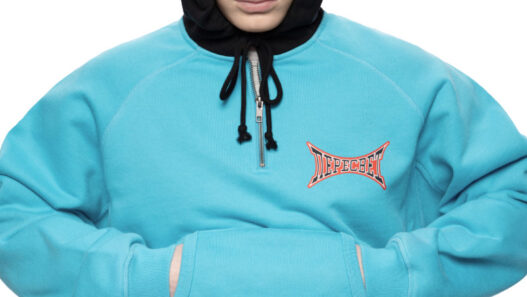 Model wearing a turquoise hoodie and pants with a black hooded balaclava; branded chest logo visible. Gosha Rubchinskiy unveils his bold new “PERESVET” campaign exploring athletic form.vGosha Rubchinskiy unveils his bold new “PERESVET” campaign exploring athletic form. Gosha Rubchinskiy unveils his bold new “PERESVET” campaign exploring athletic form.