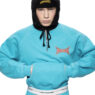 Model wearing a turquoise hoodie and pants with a black hooded balaclava; branded chest logo visible. Gosha Rubchinskiy unveils his bold new “PERESVET” campaign exploring athletic form.vGosha Rubchinskiy unveils his bold new “PERESVET” campaign exploring athletic form. Gosha Rubchinskiy unveils his bold new “PERESVET” campaign exploring athletic form.