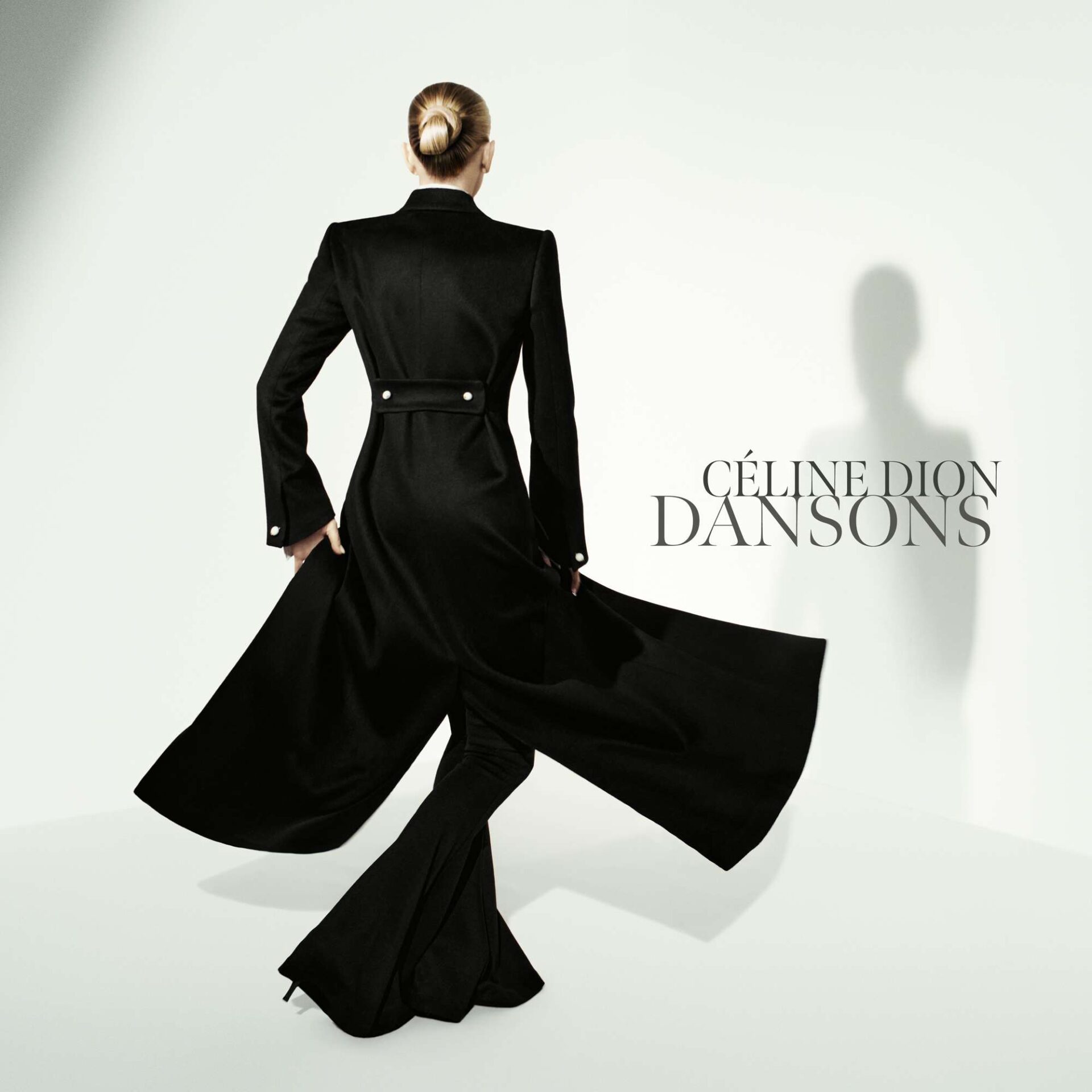 Back view of a woman in a long black coat with a flowing cape against a pale background; 'CÉLINE DION DANSONS' text on the right.