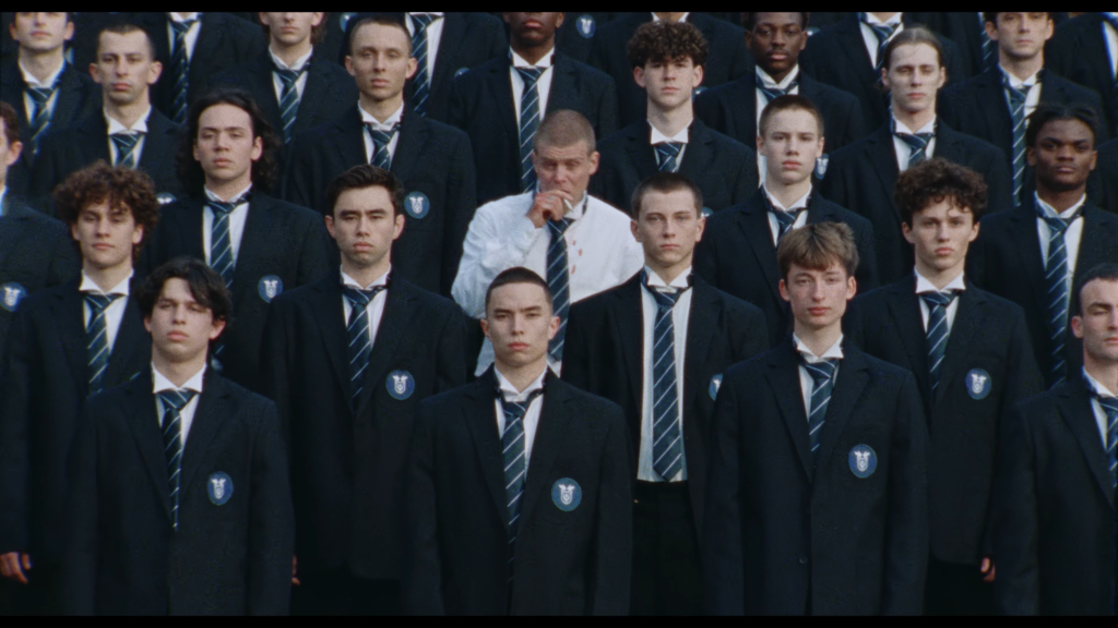 Group of male students in navy blazers with striped ties posing for a class photo.
