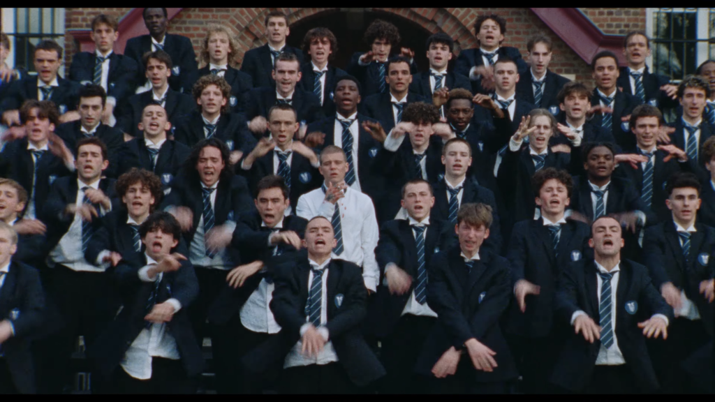 Large group of schoolboys in blazers and striped ties cheering on a staircase in front of a brick building.