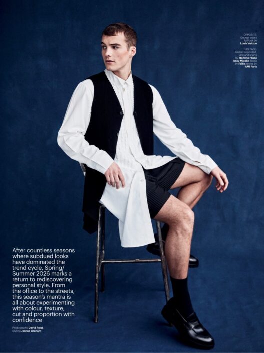 Male fashion model seated on a metal chair against a dark blue studio backdrop, wearing a white shirt with a black vest and shorts; editorial page with text blocks along left and small captions on right.
