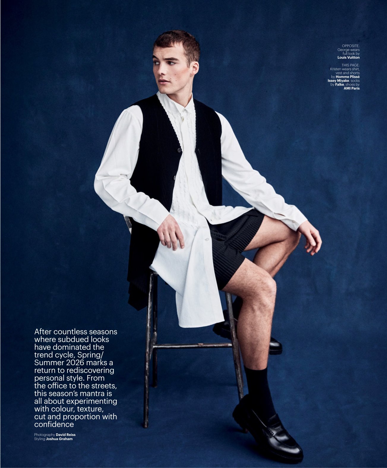 Male fashion model seated on a metal chair against a dark blue studio backdrop, wearing a white shirt with a black vest and shorts; editorial page with text blocks along left and small captions on right.