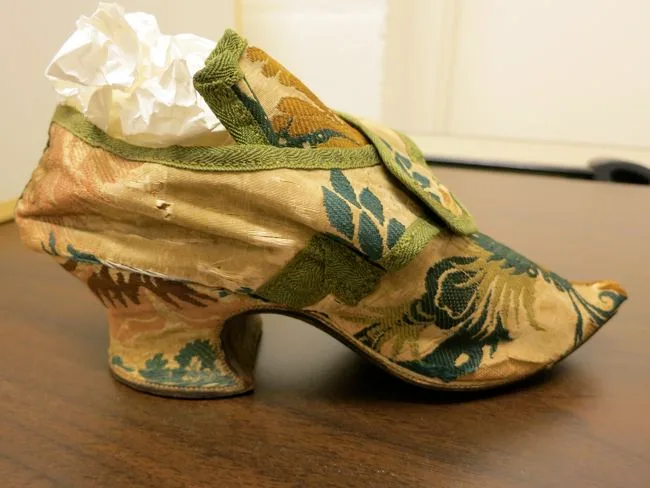 18th‑century pink silk‑covered heeled shoe undergoing conservation.