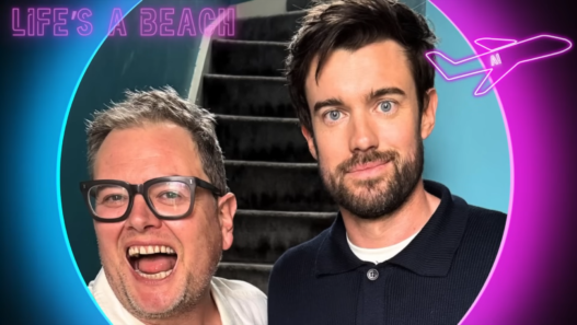 Two men smiling for a selfie in front of a stairwell, with a neon circular border and a pink airplane graphic in the corner.