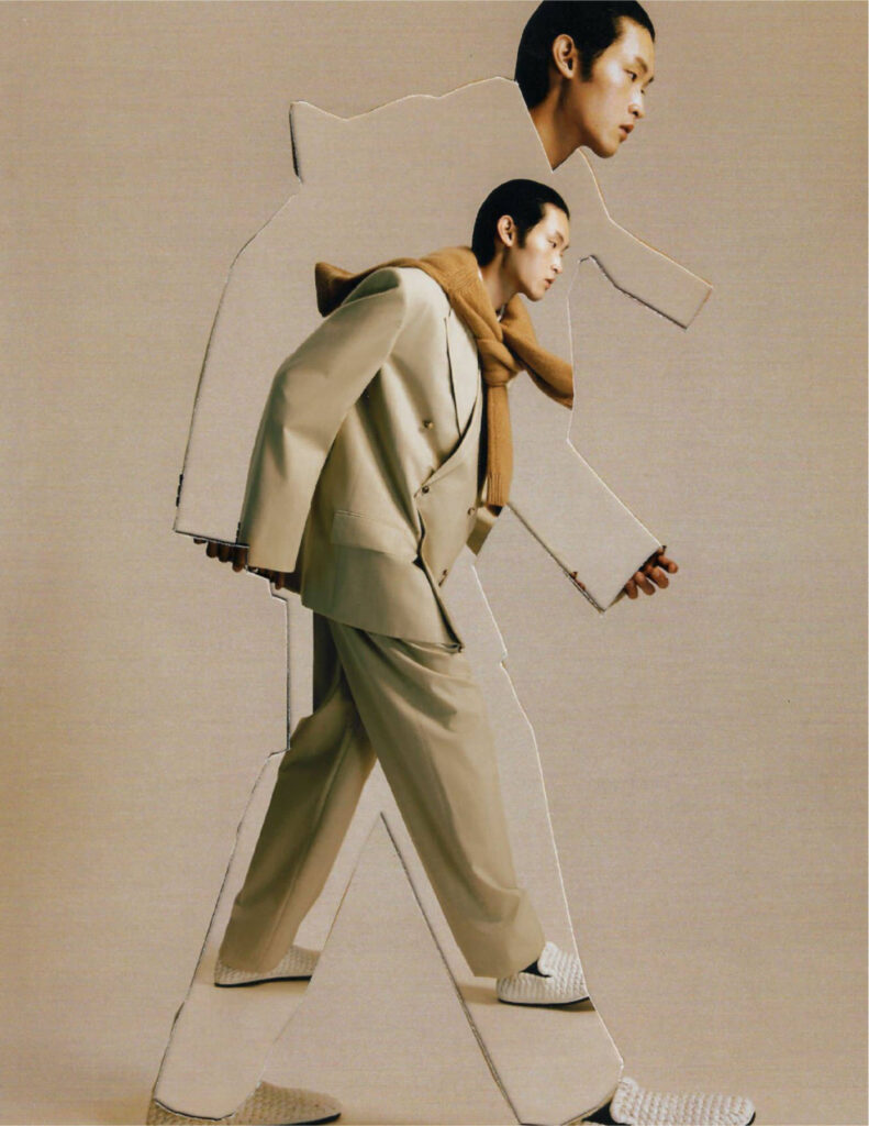 Man in a beige suit and tan scarf walks forward, with oversized cardboard cut-out silhouettes layered around him as a collage element.