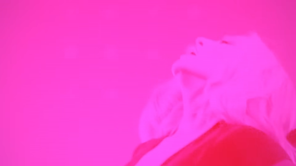 Portrait of a person lying on their side with a vivid pink color overlay.