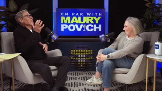 Two podcast hosts sit in armchairs facing each other, smiling and talking, with a blue sign reading 'ON PAR WITH MAURY POVICH' behind them and a rack of golf balls between.