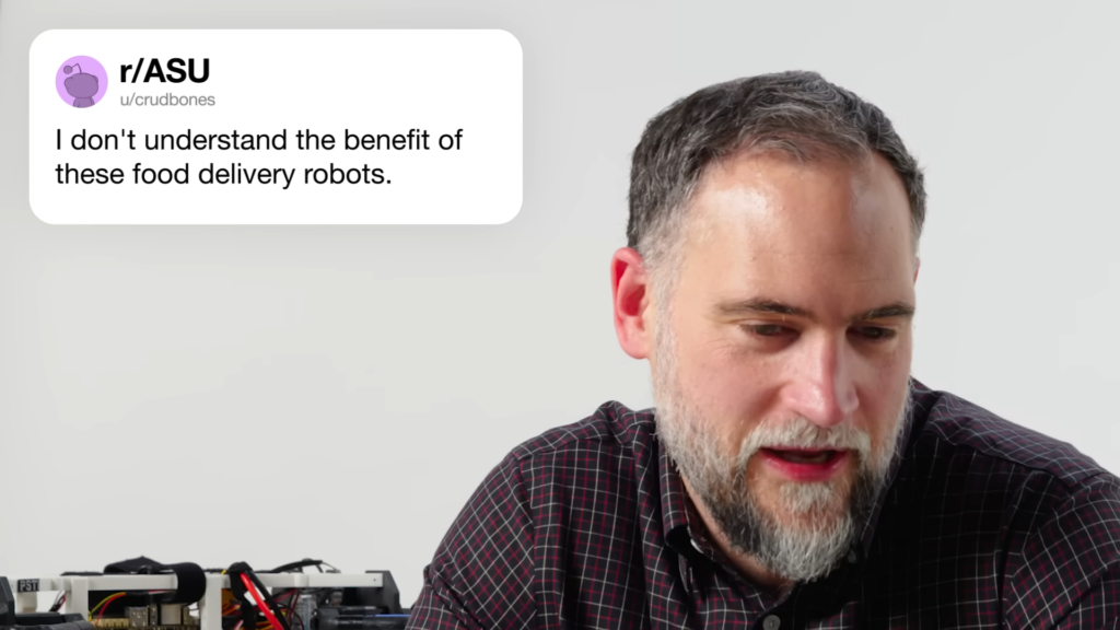 Bearded man looking down at an electronics project on a workbench; a white rounded panel on the left shows 'r/ASU' and 'u/crudbones'.