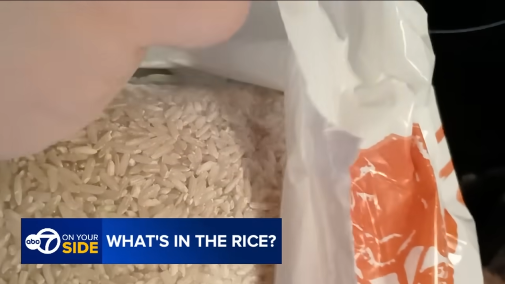 Close-up of a bag of white rice with a hand scooping grains; on-screen banner reads 'What’s in the Rice?'