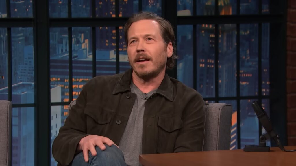 Scott MacArthur seated on the Late Night With Seth Meyers set during his interview segment.