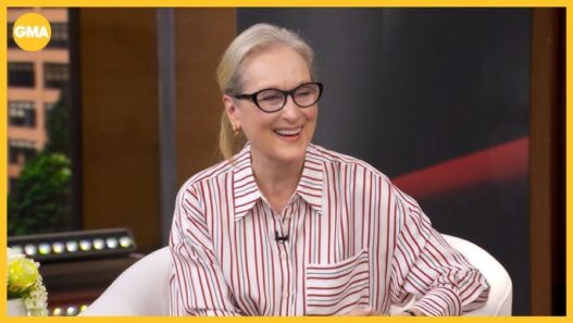 Smiling blonde woman with black glasses in a red-striped shirt on a TV morning-show set (GMA).
