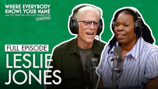 Podcast thumbnail featuring Leslie Jones and a male host wearing headphones and speaking into microphones on a green background (episode title: Full Episode Leslie Jones)