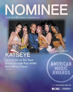 Poster advertising the American Music Awards with six women posing together; large NOMINEE text at the top and Katseye highlighted as New Artist of the Year nominee.