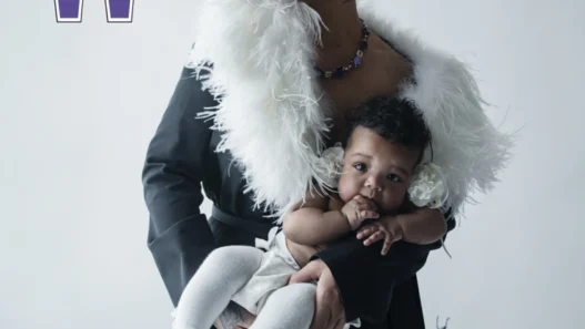 Rihanna wearing a purple hat and a white feathered scarf, holding her baby on a W magazine cover.