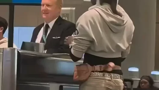 Passenger standing at airport desk with a cat sitting on his head.