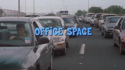 A scene from the 1999 film Office Space featuring characters in a software office setting.