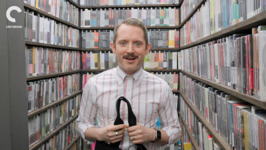 Elijah Wood standing in the Criterion Closet choosing films for his Closet Picks episode