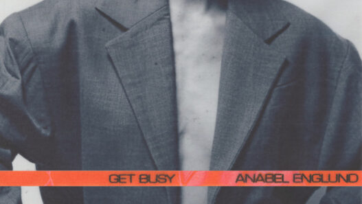 Album cover for Anabel Englund's 'Get Busy' featuring a person in an oversized gray blazer with an orange band across the chest.