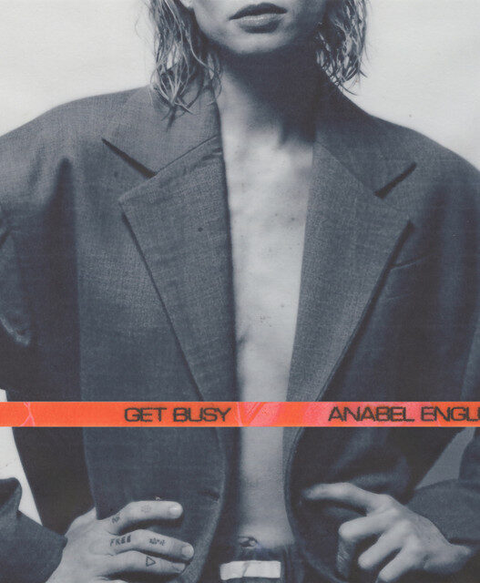 Album cover for Anabel Englund's 'Get Busy' featuring a person in an oversized gray blazer with an orange band across the chest.