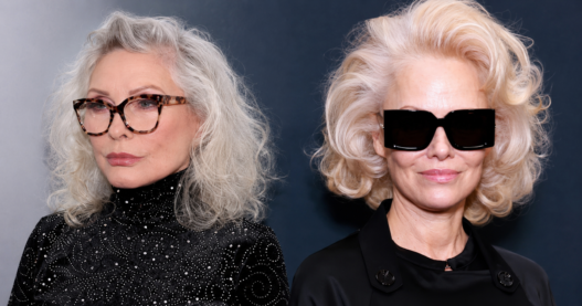 Side-by-side cropped headshot composite of Debbie Harry and Pamela Anderson in sleek black fashion looks, styled with silver and platinum blonde hair for an entertainment story header.