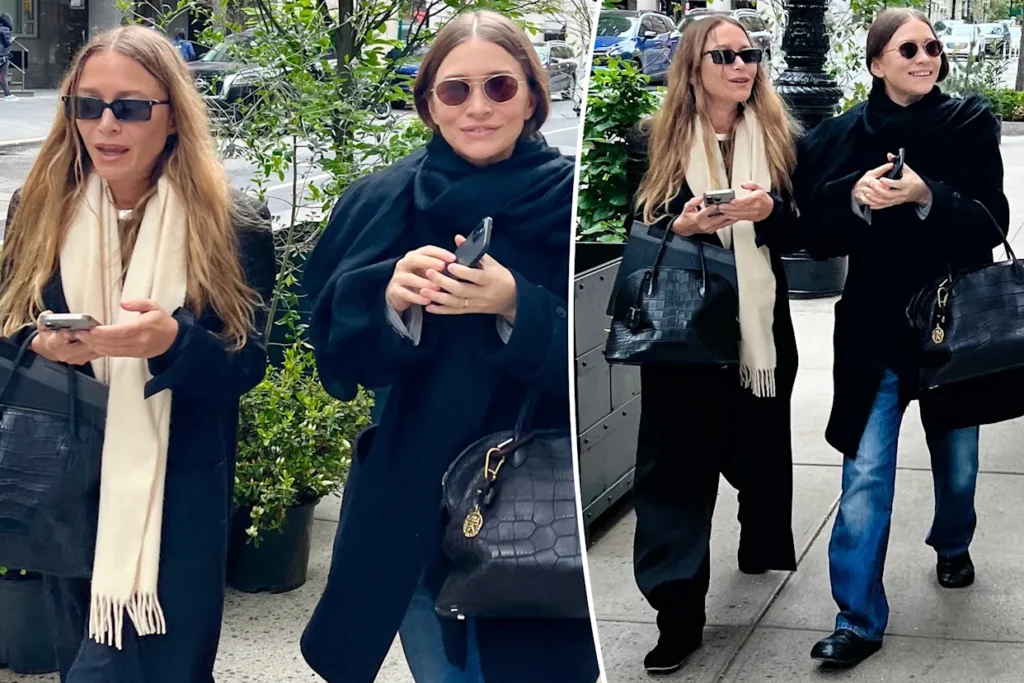 Split-image photo of two women walking on a city sidewalk: both wearing dark coats and sunglasses, each holding a smartphone and carrying a black handbag with a gold emblem; scarves around their necks.