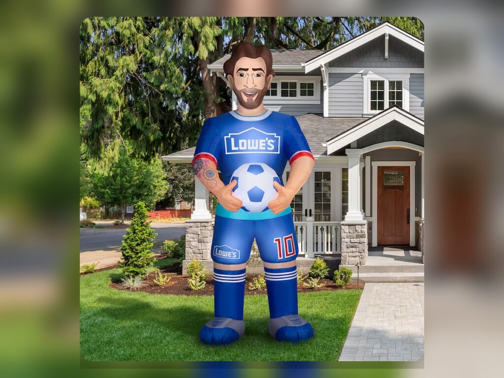 A 10-foot Lionel Messi inflatable wearing a blue Lowe’s soccer kit and holding a soccer ball in a suburban front yard.
