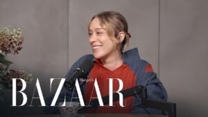 Woman smiling and speaking into a microphone during a podcast interview, with Harper's Bazaar logo overlaid.