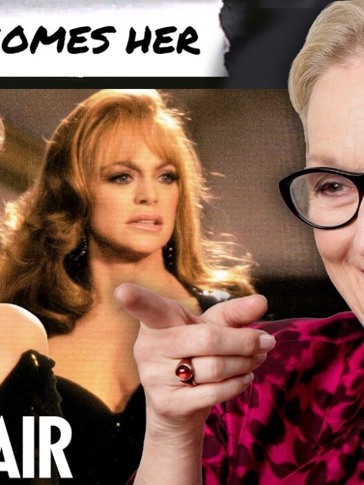 Collage: two women in elegant dresses on the left, older woman with glasses on the right smiling and pointing; 'Death Becomes Her' banner top, 'Vanity Fair' text bottom left.