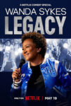 Poster for Wanda Sykes: LEGACY, a Netflix comedy special. Wanda Sykes holds a microphone, wearing a blue varsity jacket, with 'LEGACY' in large letters above. Premieres May 19 on Netflix.