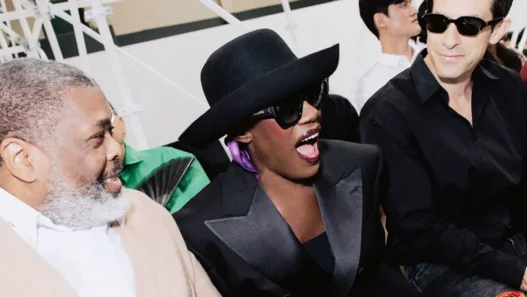 Grace Jones at the CELINE Spring Summer 2027 men’s show wearing a charcoal suit bowler hat and sunglasses