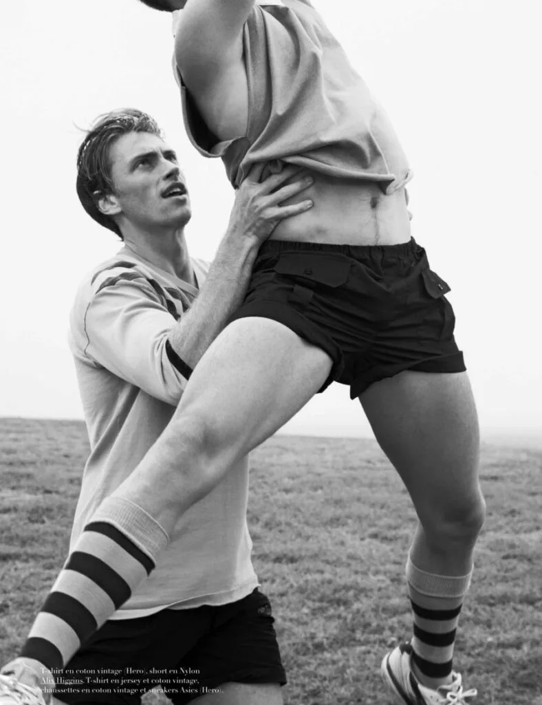 Two Bazaar Sport models perform a partner-assisted athletic movement in vintage sportswear